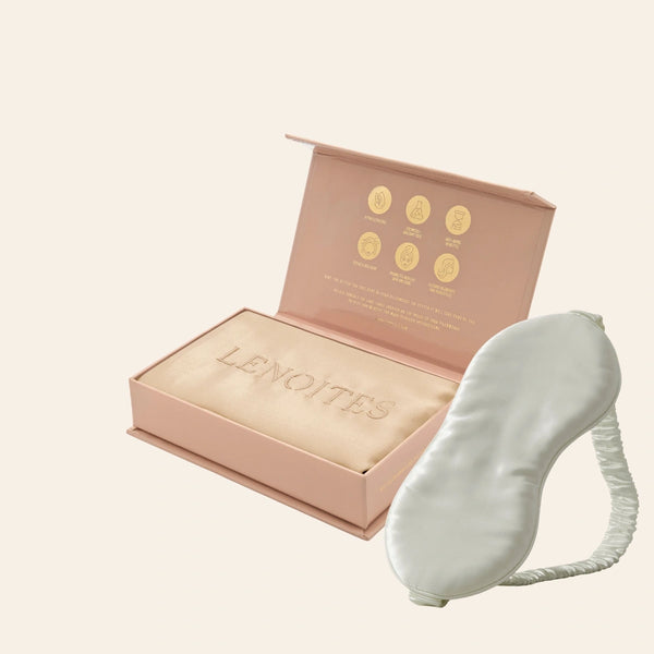 Pillowcase and Sleep Mask in Mulberry Silk by Lenoites featuring a grey silk sleep mask and a beige mulberry silk pillowcase presented in an open blush pink box against a soft light background.