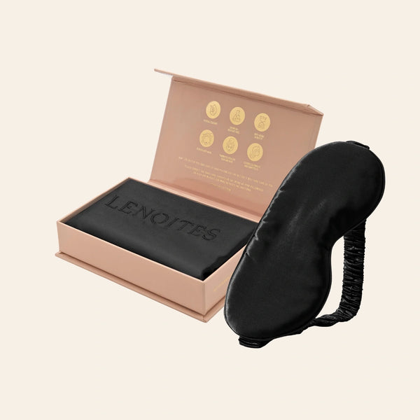 Pillowcase and Sleep Mask in Mulberry Silk by Lenoites featuring a black silk sleep mask and a black mulberry silk pillowcase presented in an open blush pink box against a soft light background.