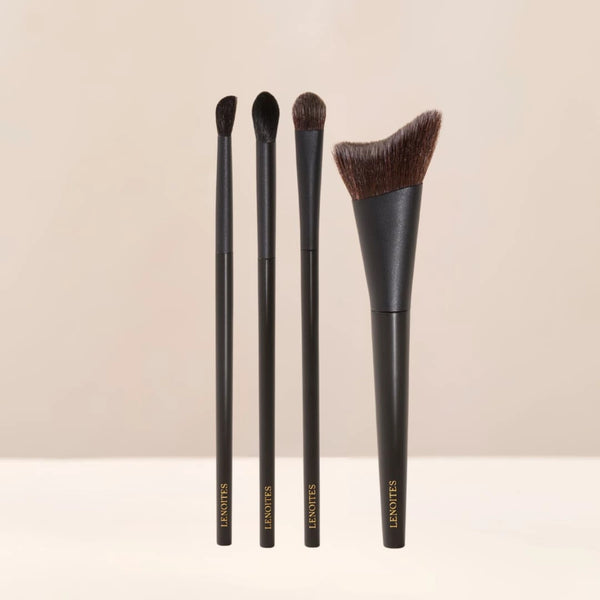 Brush Collection by Lenoites featuring four elegant makeup brushes with black handles and soft bristles, displayed against a soft beige background.