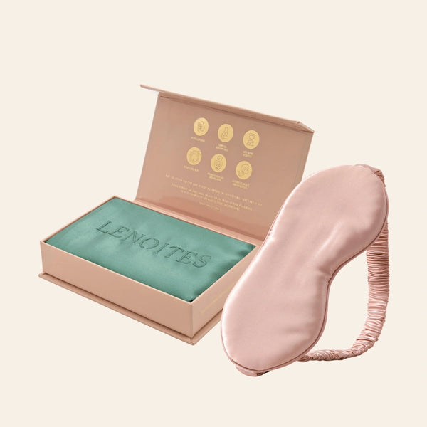 Pillowcase and Sleep Mask in Mulberry Silk by Lenoites featuring a pink silk sleep mask and a green mulberry silk pillowcase presented in an open blush pink box against a soft light background.