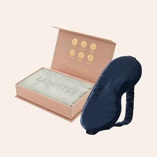 Pillowcase and Sleep Mask in Mulberry Silk by Lenoites featuring a blue silk sleep mask and a grey mulberry silk pillowcase presented in an open blush pink box against a soft light background.
