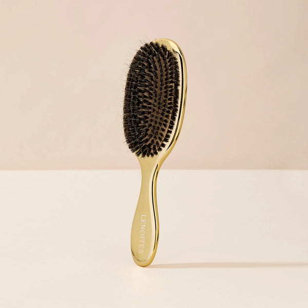 Wild Boar Hair Brush in Gold by Lenoites, featuring a sleek handle and bristles, displayed against a soft beige background.