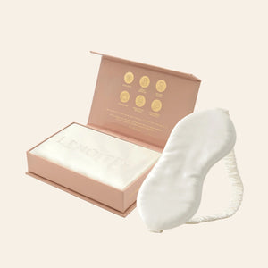 Pillowcase and Sleep Mask in Mulberry Silk by Lenoites featuring a white silk sleep mask and a white mulberry silk pillowcase presented in an open blush pink box against a soft light background.
