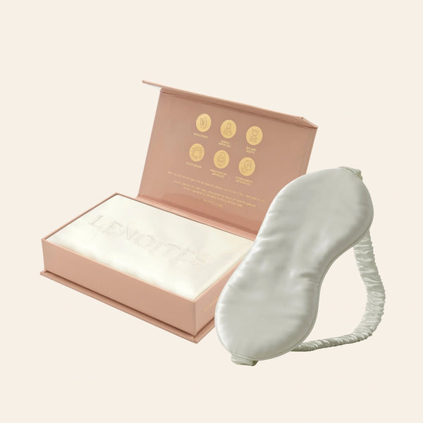 Pillowcase and Sleep Mask in Mulberry Silk by Lenoites featuring a grey silk sleep mask and a white mulberry silk pillowcase presented in an open blush pink box against a soft light background.